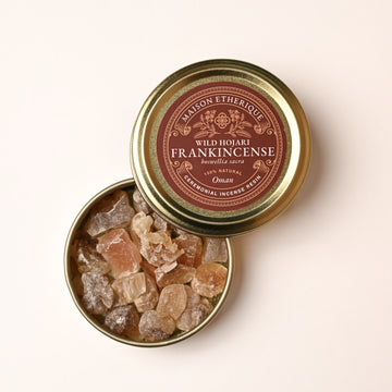 Open gold tin of Maison Éthérique Wild Hojari frankincense (Boswellia sacra) from Oman, pale resin tears visible inside.