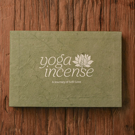 Closed Yoga Incense gift box in green handmade paper on a wooden surface.